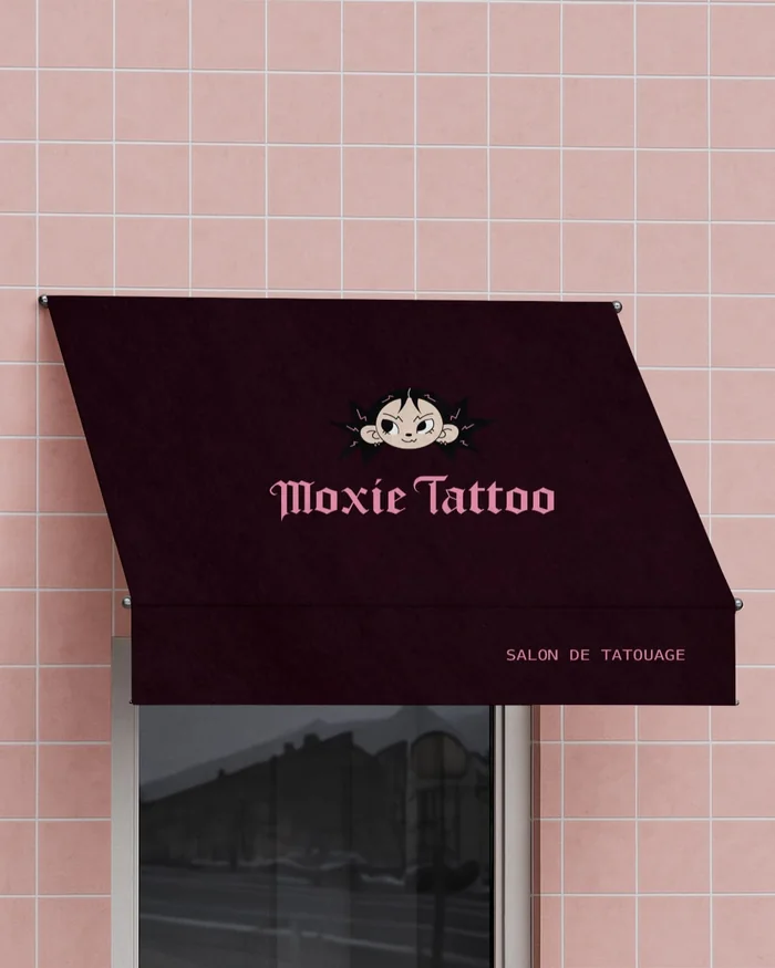 Store bordeaux du salon Moxie Tattoo sur une façade carrelée rose.