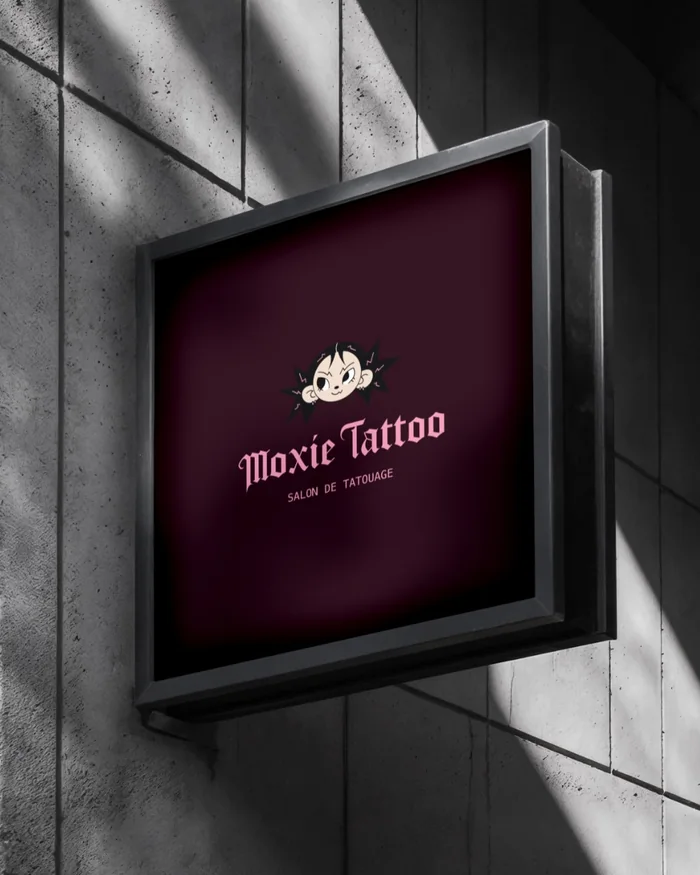 Caisson lumineux Moxie Tattoo en applique sur un mur de béton.